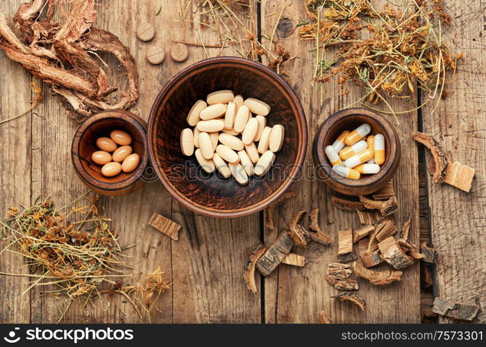 Herbal medical tablets with healing plant on wooden table.Alternative medicine tablets. Vitamins, tablets and pills