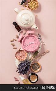Herbal medicine for treat depression and insomnia concept. Alarm clock, sleep mask, medicine herbs, capsules, camomile tea and aromatherapy oil on pink background, top view