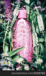 Herbal or floral cosmetic product bottle on herbs and flowers background , top view. Skincare , wellness, Natural cosmetic and beauty concept