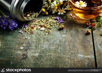 Herbal tea and wild organic flowers on wooden background
