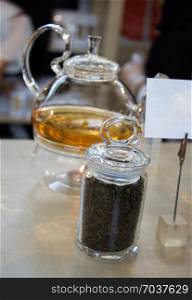 Herbal tea brewed in glass teapot and tea plant in a bottle