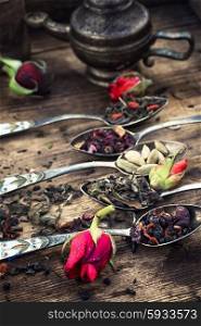 Herbal tea collection variety. Vintage spoons with different varieties of tea on vintage wooden plank background.