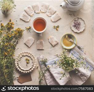 Herbal tea concept. Healthy hot drink. Various fresh medical herbs with cup of herbal tea, honey and tea bags on rustic table background. Top view
