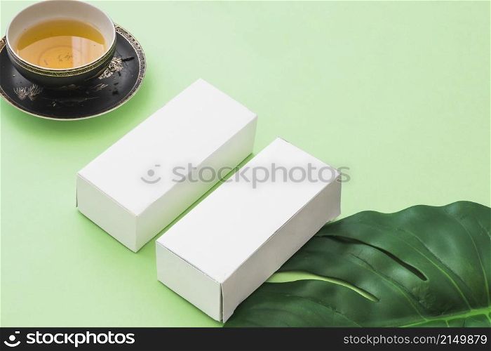 herbal tea cup two white boxes with leaf green background
