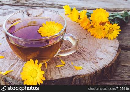 Herbal tea from calendula flowers in a transparent glass mug. Extract of tincture of calendula in the cup. Medicinal plants.. Herbal tea from calendula flowers in a transparent glass mug. Extract of tincture of calendula in the cup.