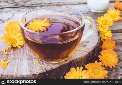 Herbal tea from calendula flowers in a transparent glass mug. Extract of tincture of calendula in the cup. Medicinal plants.. Herbal tea from calendula flowers in a transparent glass mug. Extract of tincture of calendula in the cup.