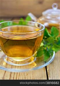 Herbal tea in a glass cup and teapot from mint, fresh mint leaves on wooden board