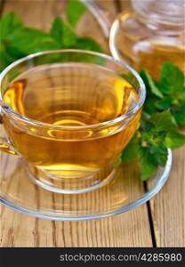 Herbal tea in a glass cup and teapot from mint, fresh mint leaves on a wooden boards background
