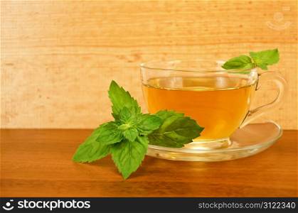 Herbal tea in a glass cup with mint on a table on the background of wooden boards