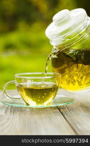 Herbal tea in a glass teapot on the table outdoor. The Herbal tea