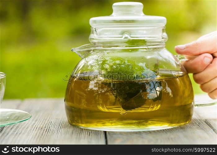 Herbal tea in a glass teapot on the table outdoor. The Herbal tea