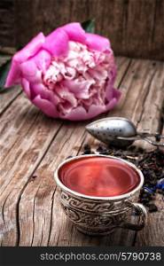 herbal tea. iron bowls with herbal tea on the background of the peony bud and scattered welding elite tea.Selective focus.Photo tinted