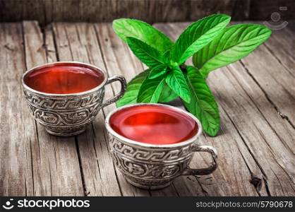 herbal tea. two iron bowls with herbal tea on background of mint leaves