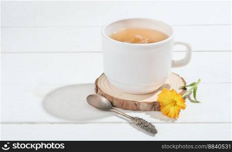 herbal tea with calendula on a white wooden table. alternative medicine for gastrointestinal system health and anxiety relief. calming and soothing evening drink.. herbal tea with calendula on a white wooden table. alternative medicine for gastrointestinal system health and anxiety relief. calming and soothing evening drink