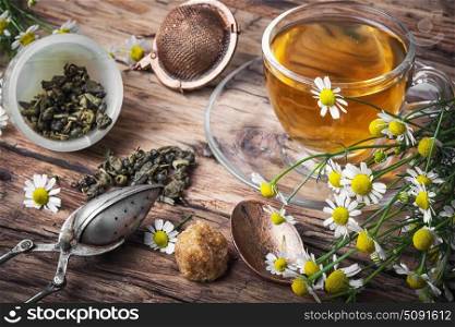 Herbal tea with chamomile. cup with chamomile tea, tea strainer, chamomile flowers on rustic wooden background