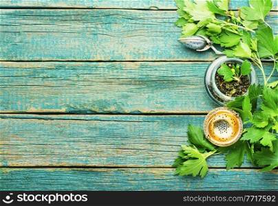 Herbal tea with fresh currant foliage.Herbal medicine.Copy space. Healing tea with raw currant leaves,wooden background