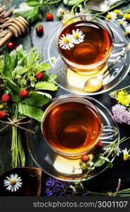 Herbal tea with honey, wild berry and flowers on wooden background