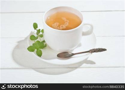 herbal tea with mint on a white wooden table. alternative medicine for gastrointestinal system health and anxiety relief. calming and soothing evening drink. . herbal tea with mint on a white wooden table. alternative medicine for gastrointestinal system health and anxiety relief. calming and soothing evening drink