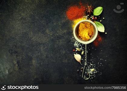 Herbs and spices selection (tumeric, paprika, basil, salt, papper) on dark rustic background. Background layout with free text space.