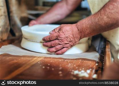 Herdsman’s hands while preparing typical northern Italian cheese with string to create classic shape 