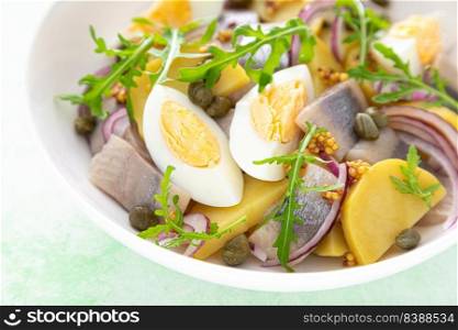 Herring and boiled potato salad with egg, capers and red onion