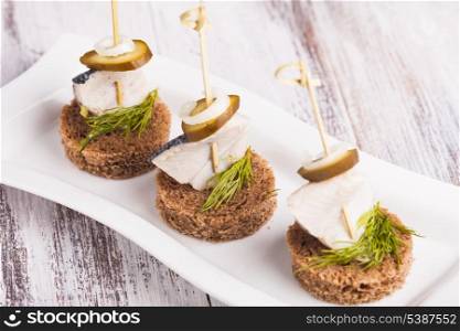 Herring canape with onion, pickled cucumber and dill