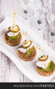 Herring canape with onion, pickled cucumber and dill