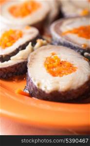 Herring rolls with carrot on orange plate closeup