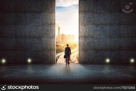 Hesitant businessman looking outside against concrete wall with huge door ,sunrise scene city skyline outdoor view .