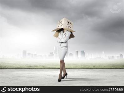 Hiding emotions. Businesswoman in suit wearing carton box on head