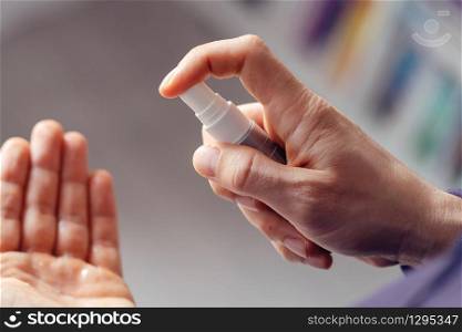 High angle close up unknown male person caucasian man applying spray disinfection alcohol product on hand disinfecting hands against virus bacteria health prevention in day at home or work