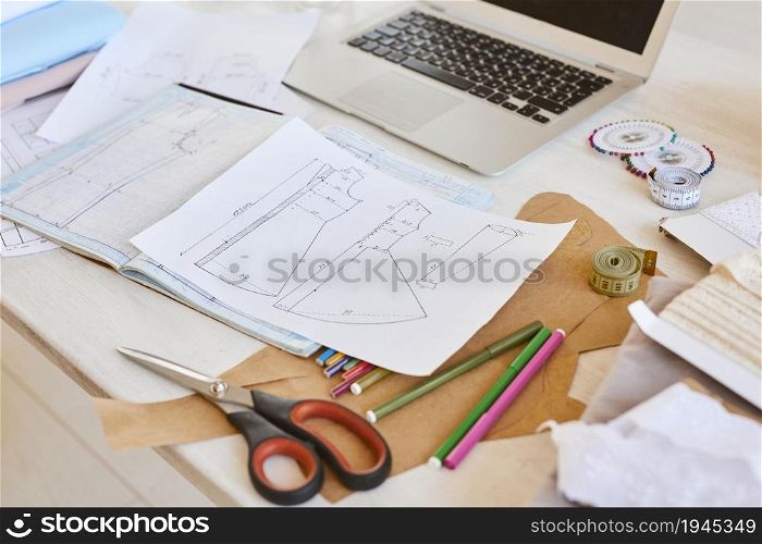 high angle clothing line plans table with laptop scissors atelier. High resolution photo. high angle clothing line plans table with laptop scissors atelier. High quality photo