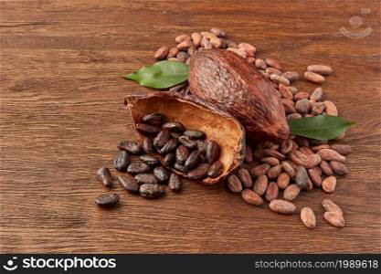 High angle composition of whole and halved cocoa pods with pile of peeled and unpeeled aromatic cocoa beans on wooden surface. Pods with peeled and unpeeled cocoa beans