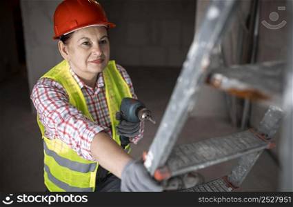 high angle female construction worker with electric drill