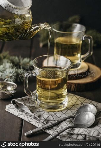 high angle hand pouring tea glass with teapot
