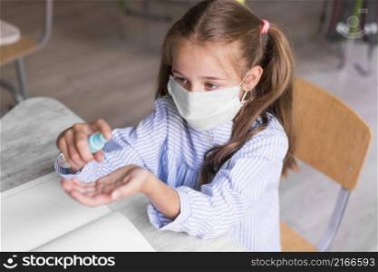 high angle kid disinfecting her hands