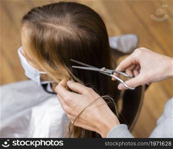 high angle little girl getting haircut while wearing medical mask. High resolution photo. high angle little girl getting haircut while wearing medical mask. High quality photo