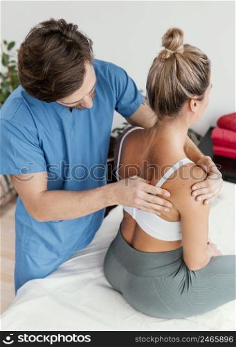 high angle male osteopathic therapist checking female patient s scapula