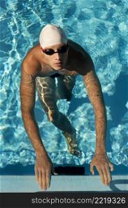 high angle male swimmer emerging out pool