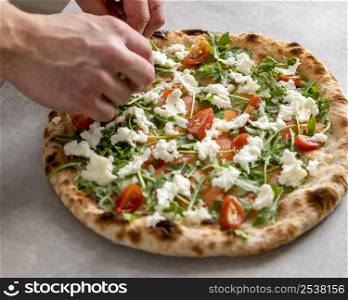 high angle man putting mozzarella baked pizza dough with smoked salmon slices