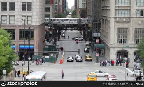 High angle of a Michigan Avenue intersection and the border of The Loop in Chicago, with traffic, pedestrians, and en el train passing by.