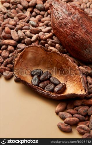High angle of half of cocoa pod filled with peeled organic beans of Theobroma cacao tree on light brown background. Peeled raw beans of cocoa in pod