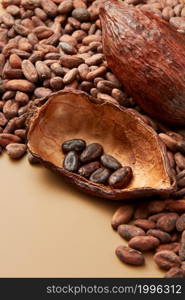 High angle of half of cocoa pod filled with peeled organic beans of Theobroma cacao tree on light brown background. Peeled raw beans of cocoa in pod