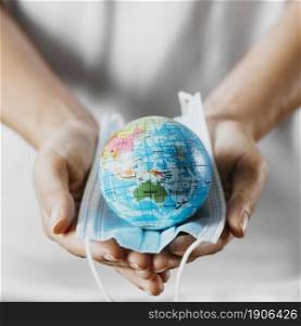 high angle person holding medical mask with earth globe. High resolution photo. high angle person holding medical mask with earth globe. High quality photo