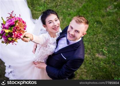 High angle portrait of cheerful wedding couple standing on grassy field