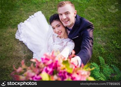 High angle portrait of happy wedding couple on grassy field