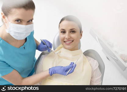 High angle portrait of smiling dentist and patient during dental treatment
