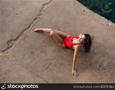 High angle portrait of young woman posing in red bathing costume on pier