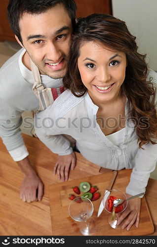 high angle shot of couple all smiles slicing fruits