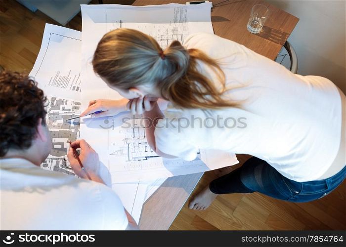 High angle shot of male and female architects at work. Woman pointing on the place on the map